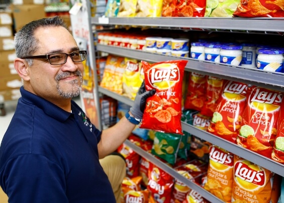 Smiling worker man taking a bag of Lays in a supermarket